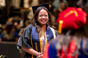 undergraduate major at commencement smiling as they walk across the stage
